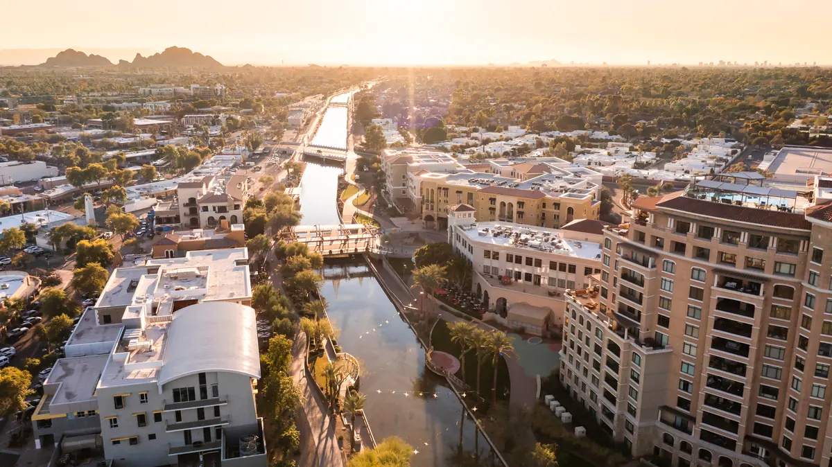 Golden-hour aerial of a canal and walking path winding through a Scottsdale residential district